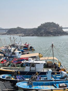Row of vibrant fishing boats docked near a picturesque island. Perfect for travel themes.