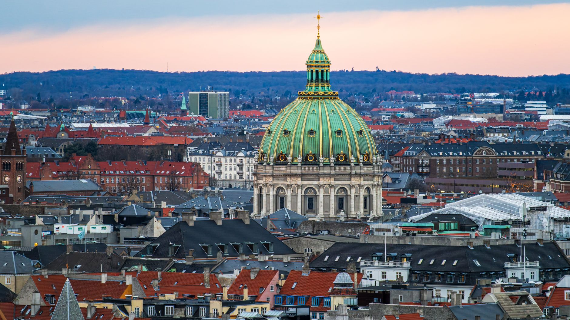 Aerial view of Frederik's Church in Copenhagen with its iconic green dome against a winter sunset.