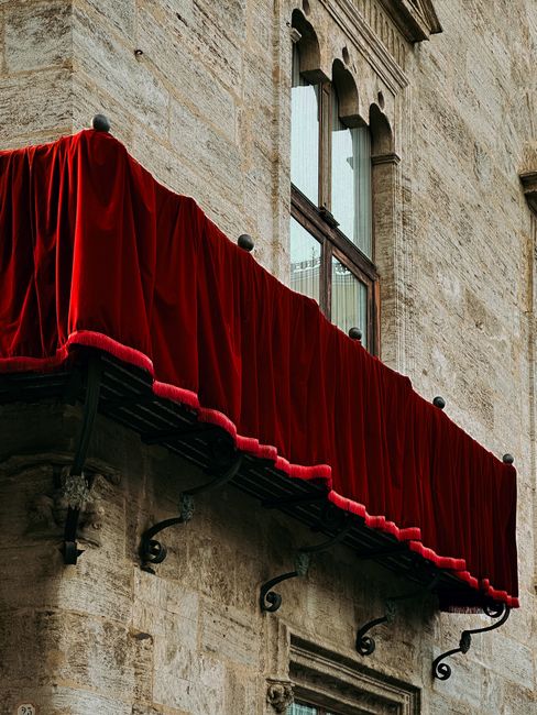 Historic architecture in Valencia with vibrant red velvet awning, showcasing classical European design.