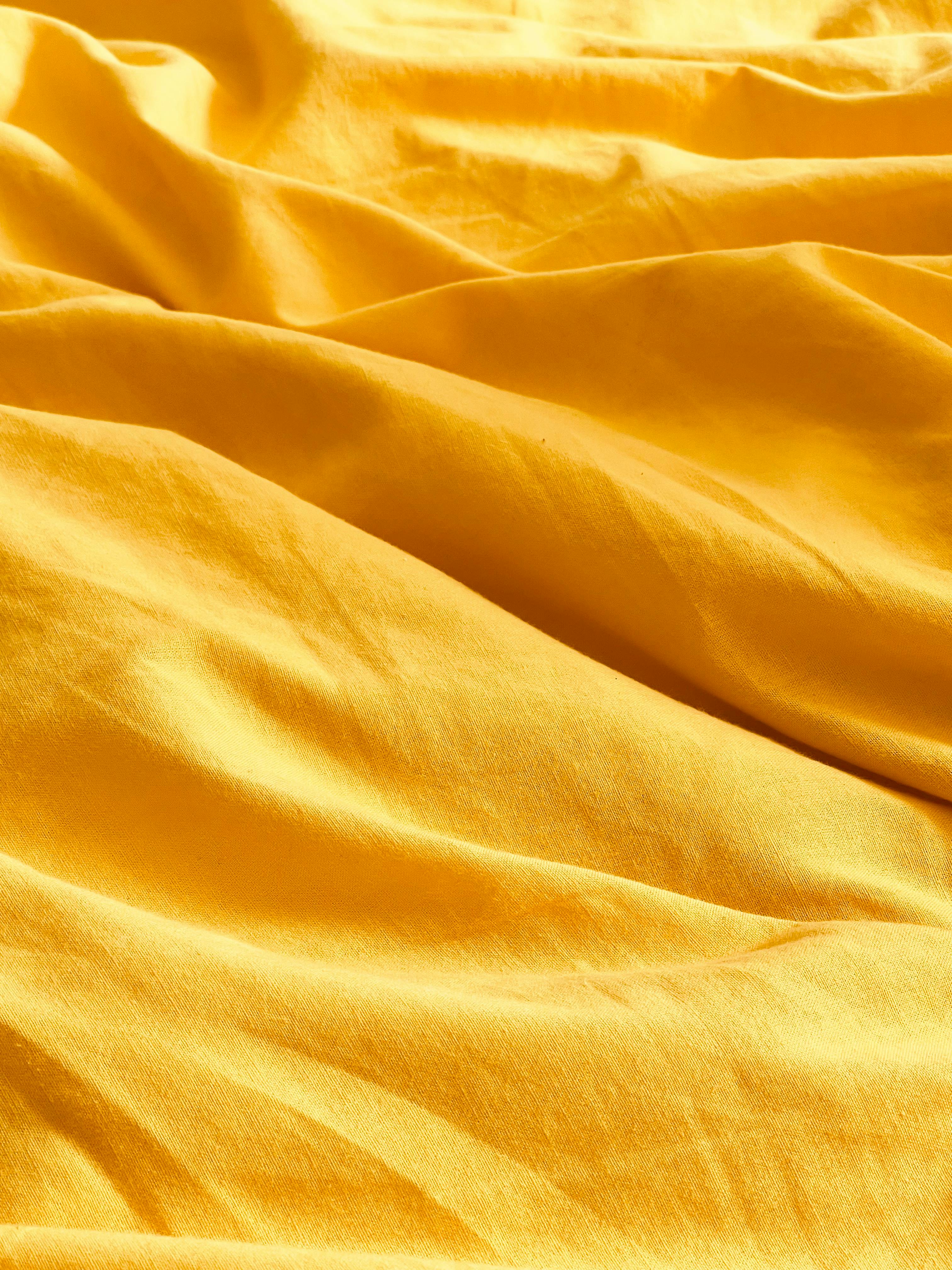 Free Bright yellow fabric with texture highlights perfect for design backgrounds and creative projects. Stock Photo