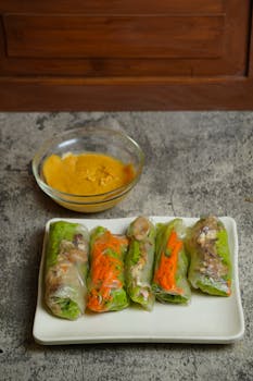 A plate of fresh Vietnamese spring rolls served with creamy peanut sauce.