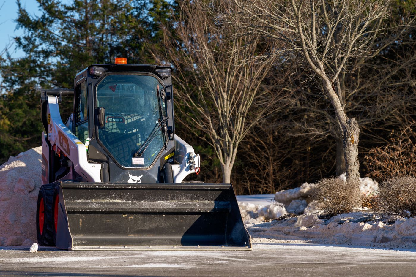 Skid steer loader clearing snow on a bright winter day