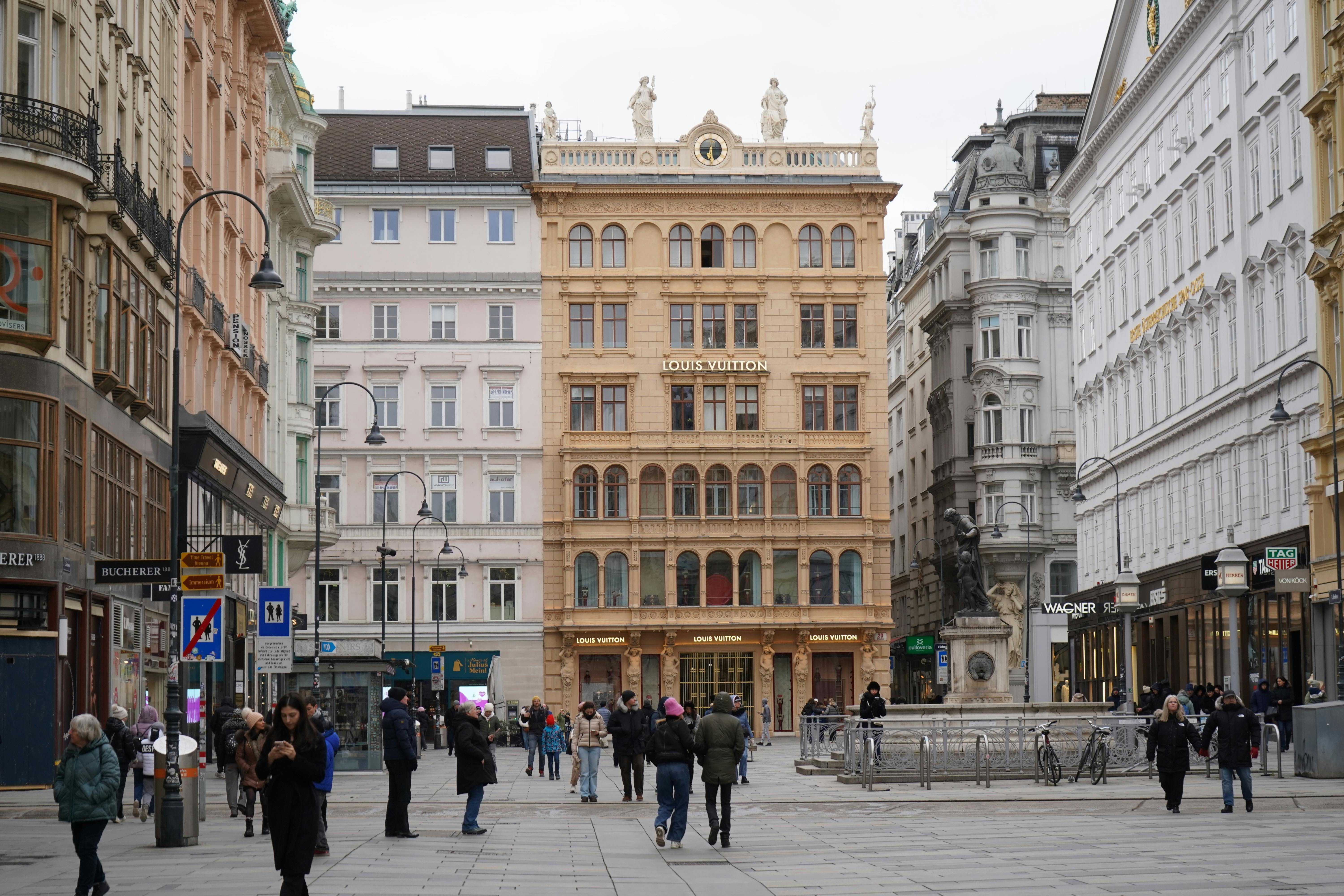 A bustling street scene in Vienna, featuring historic architecture and a Louis Vuitton store.