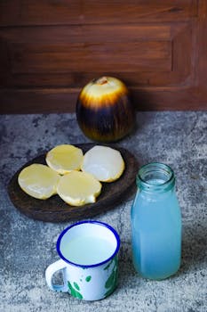 Toddy palm fruit slices with refreshing coconut water in jars and cups on textured surface.