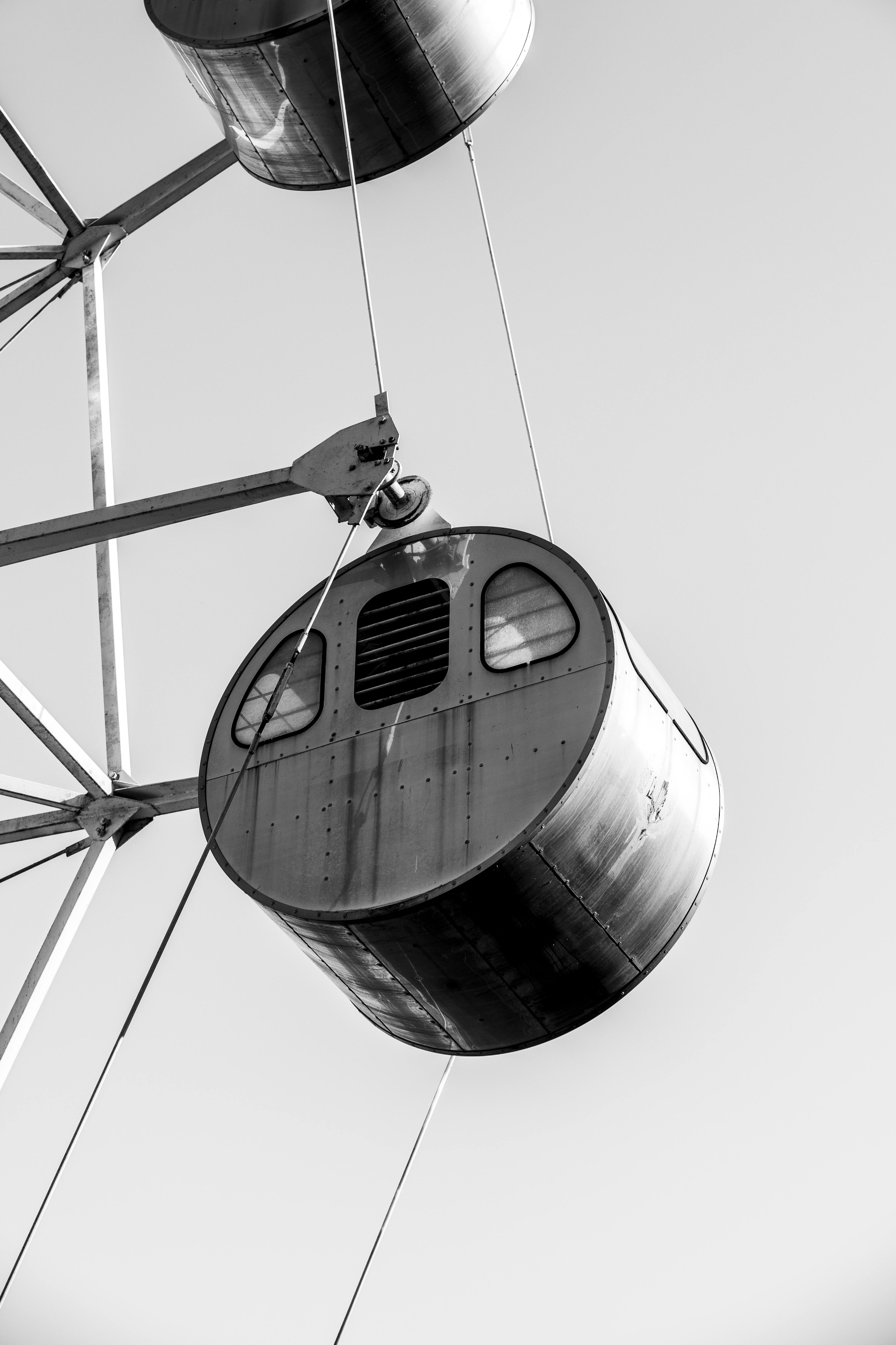 Free Black and white photo of a vintage Ferris wheel cabin against a clear sky. Stock Photo