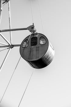Minimalistic black and white close-up of a ferris wheel capsule during the day.