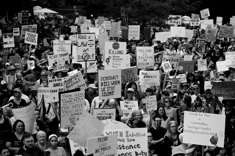 Black and white photo of a large crowd at a political protest holding various signs and slogans.
