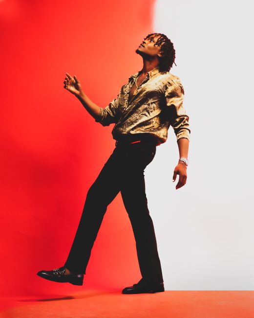 A fashionable young adult posing stylishly against a bold red and white background in a Lagos studio.