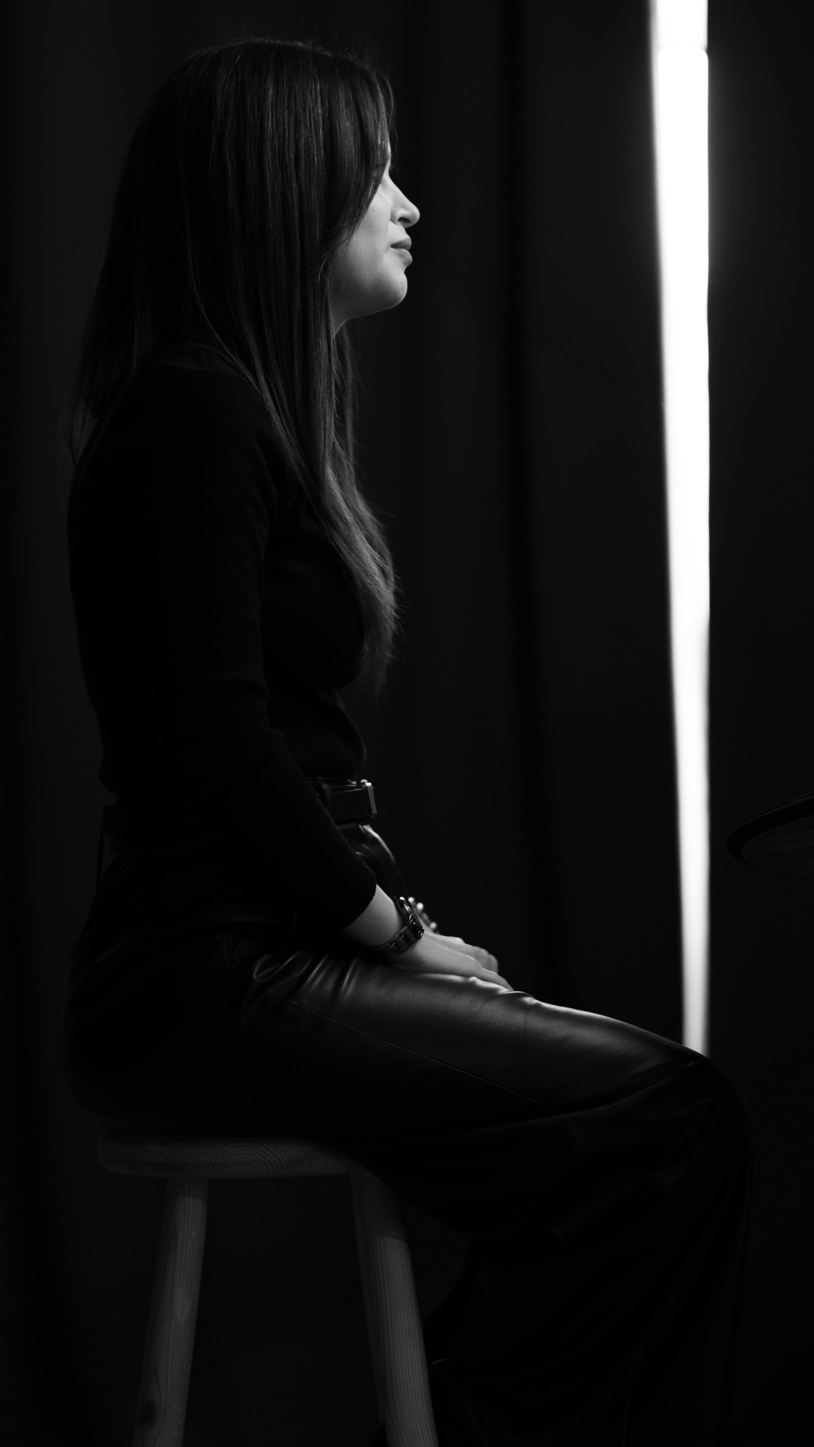 Studio side portrait of a woman in black and white, displaying elegance and poise.