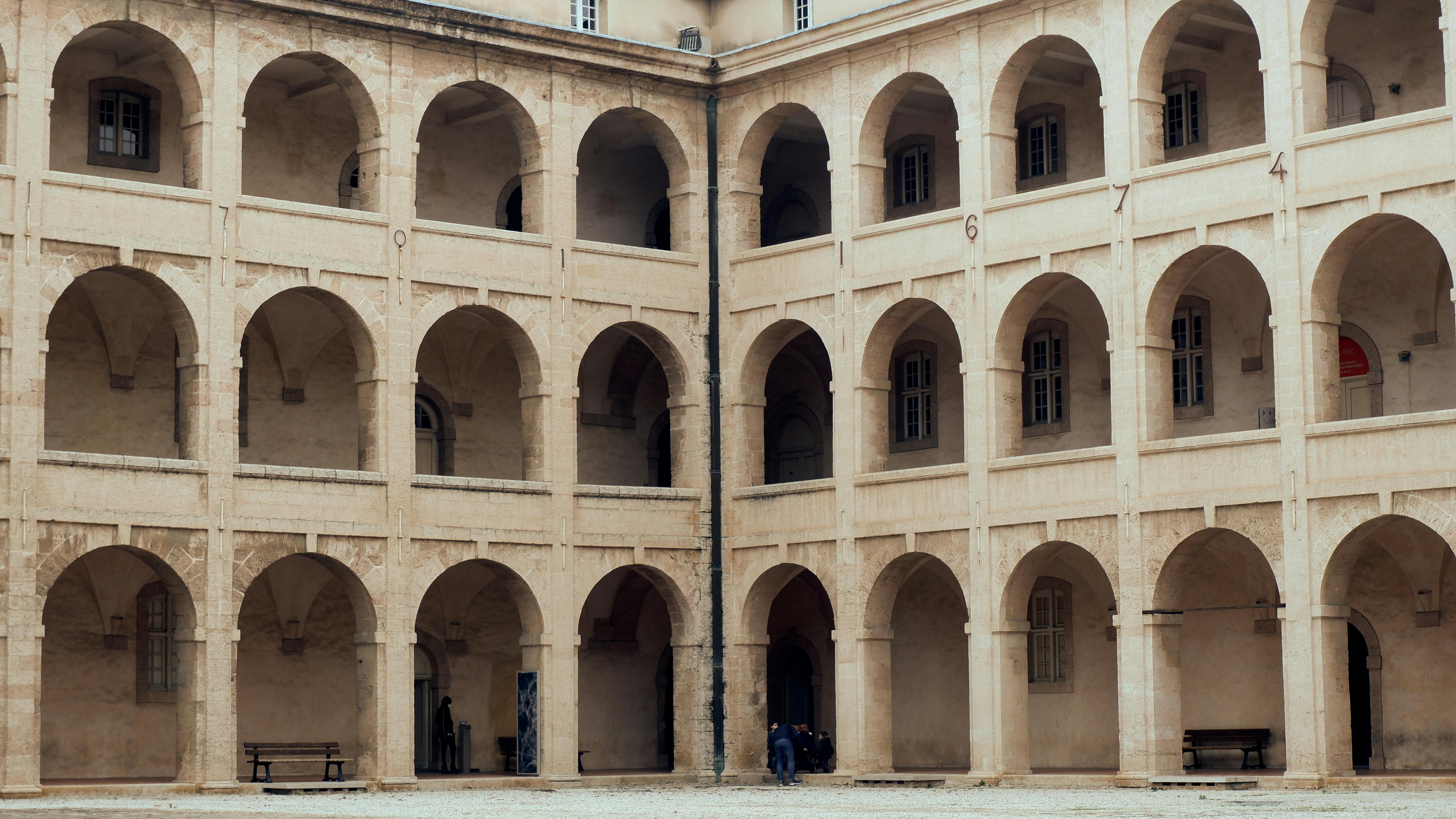 무료 마르세유의 유서 깊은 안뜰에 있는 아치형 건축물의 아름다운 모습은 우아한 디자인과 대칭미를 보여줍니다. 스톡 사진