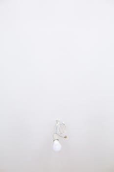 A single light bulb hanging with visible wiring in a minimalistic interior setup.