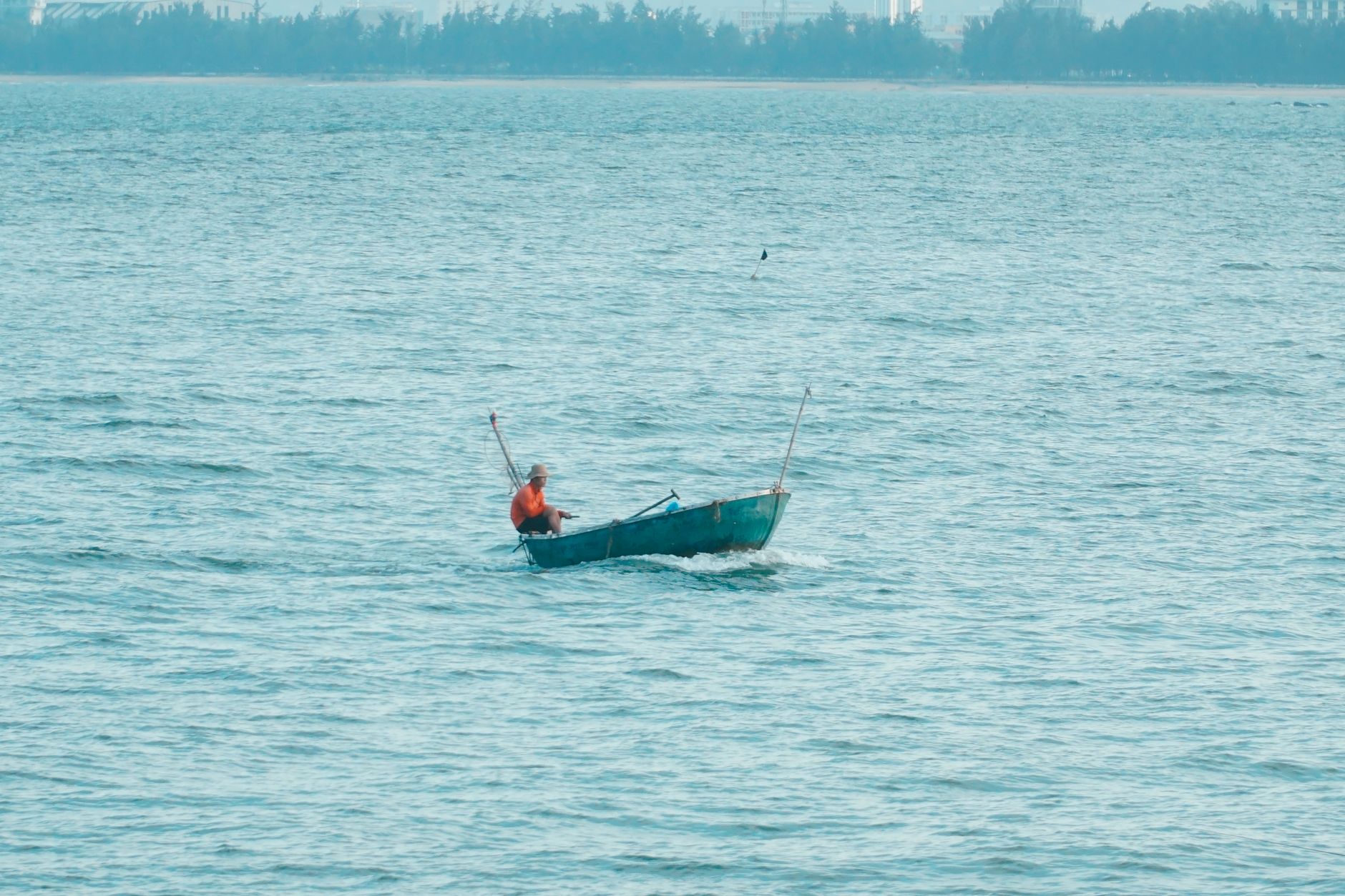 A lone fisherman rows his traditional boat on the calm waters of Da Nang, Vietnam.