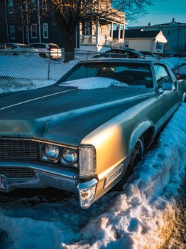 A classic vintage car parked on a snow-covered street in Revere, MA, during winter.