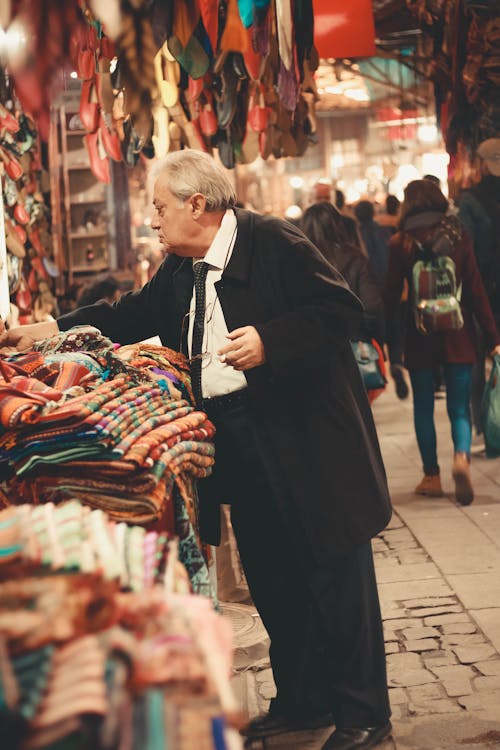 Человек в черном пальто стоит возле дисплея одежды