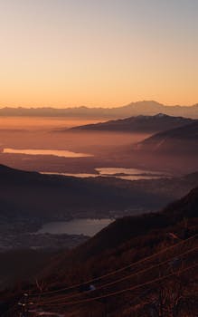 Breathtaking sunrise view over Italian mountainous landscape with lakes and mist in the distance.