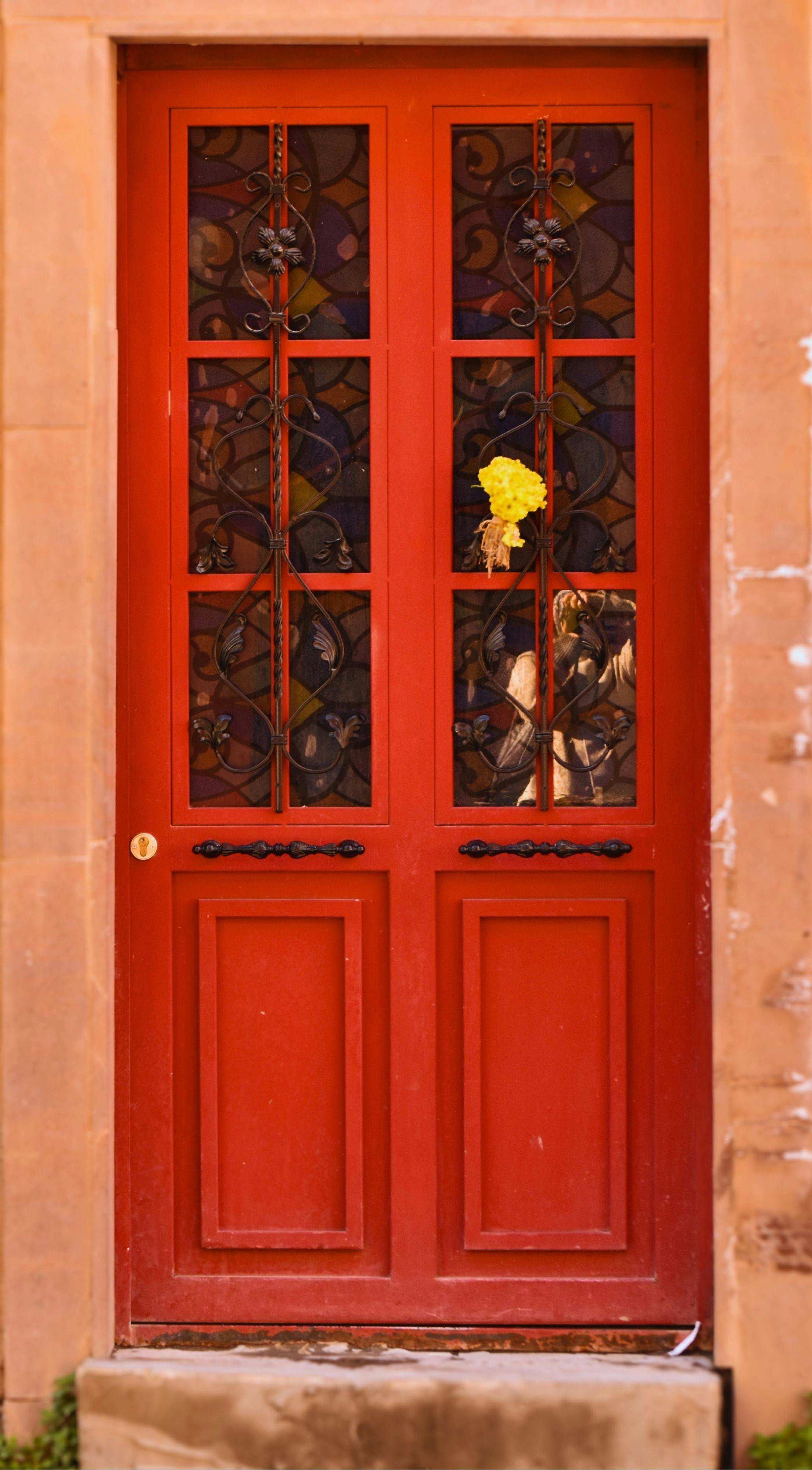 Gratis Affascinante porta rossa con grata ornamentale in ferro e un bouquet giallo in Turchia. Foto a disposizione
