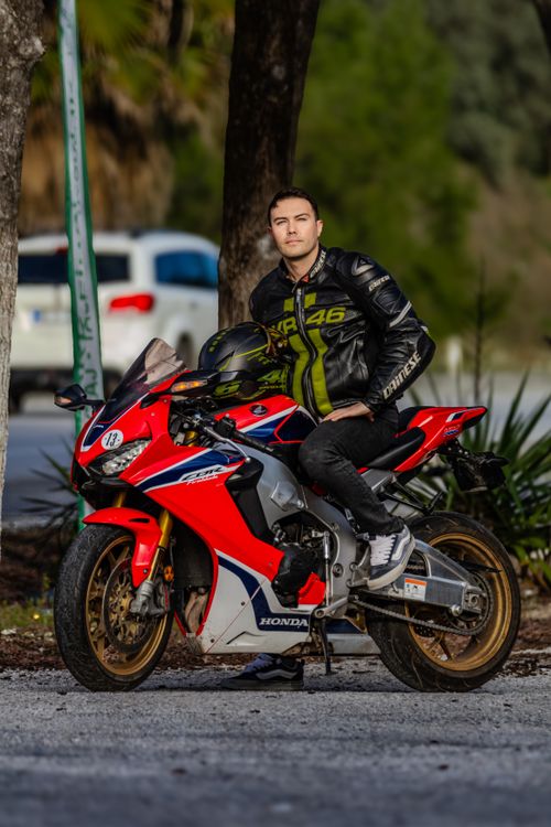 Free Man in black leather jacket sitting on a sports motorcycle in a natural setting. Stock Photo