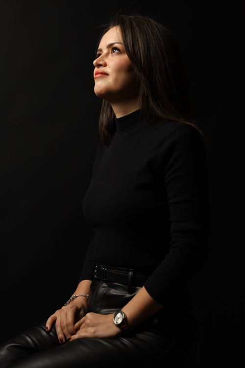 Free A stylish woman in black gazes upwards, set against a dark backdrop, capturing elegance and mystery. Stock Photo