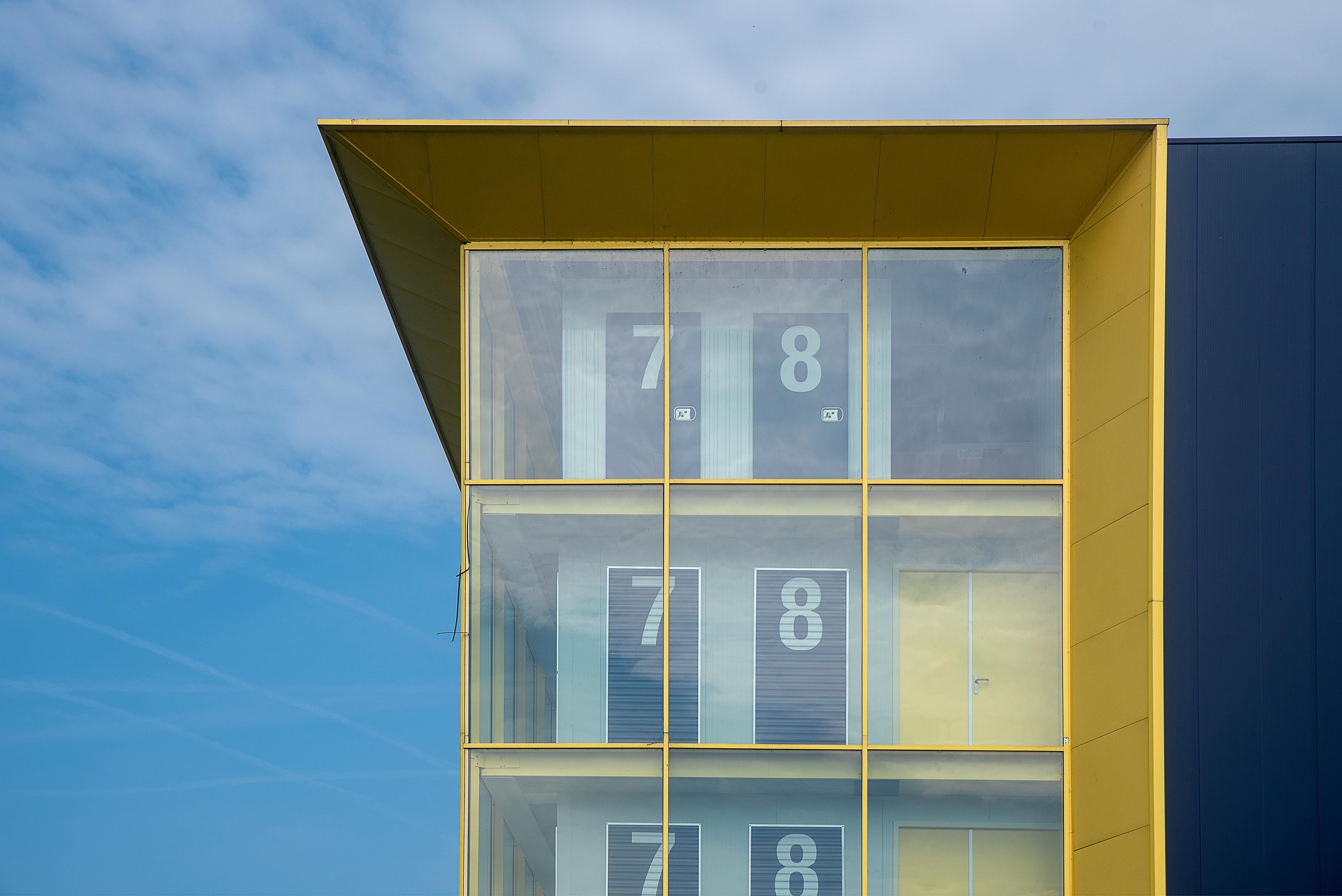 Contemporary building exterior featuring numbered transparent doors against a blue sky.