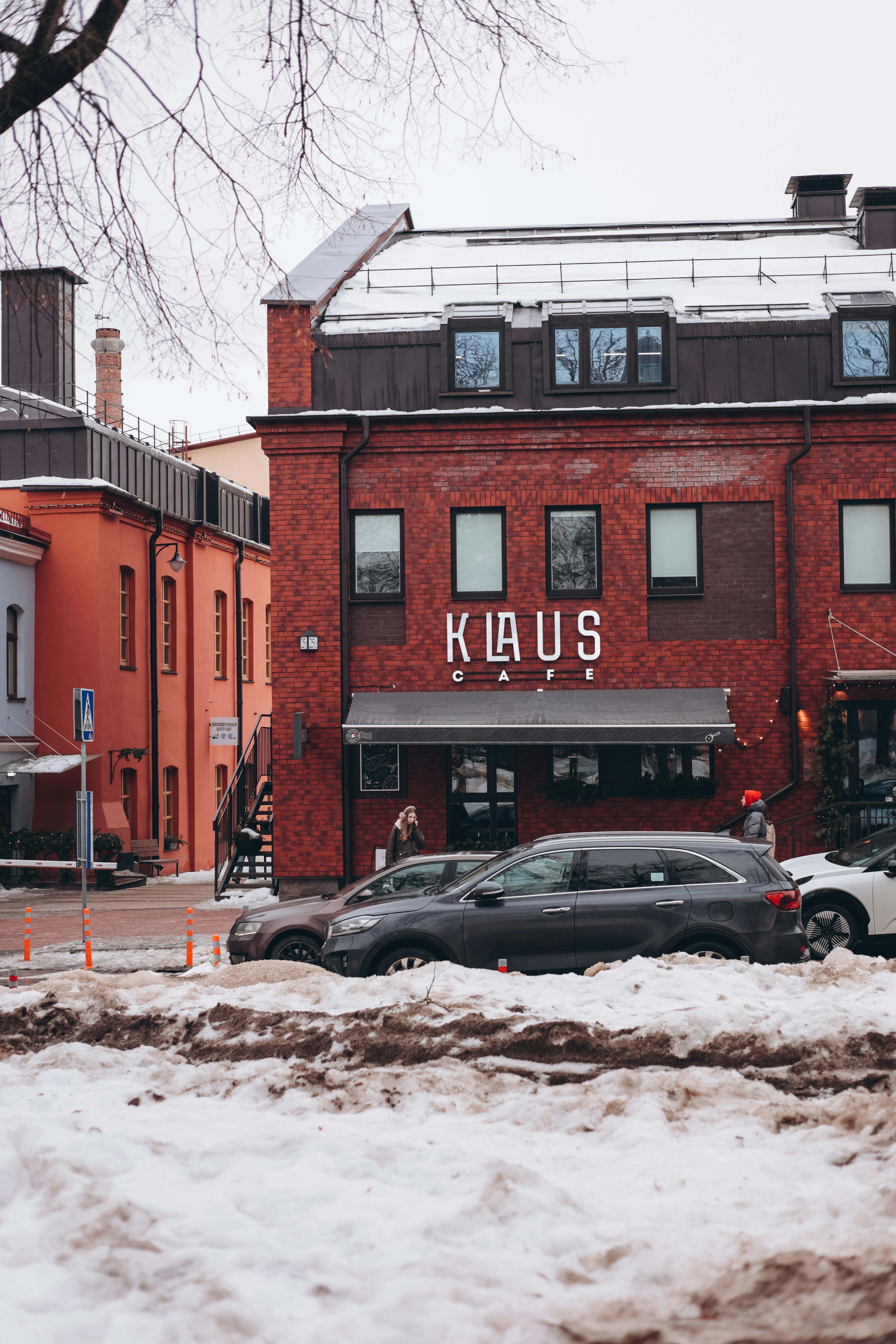 ฟรี คาเฟ่สไตล์ชนบทที่สร้างจากอิฐ ตั้งอยู่ในทิวทัศน์เมืองที่ปกคลุมไปด้วยหิมะ โดยมีรถยนต์จอดอยู่เป็นฉากหลัง คลังภาพถ่าย