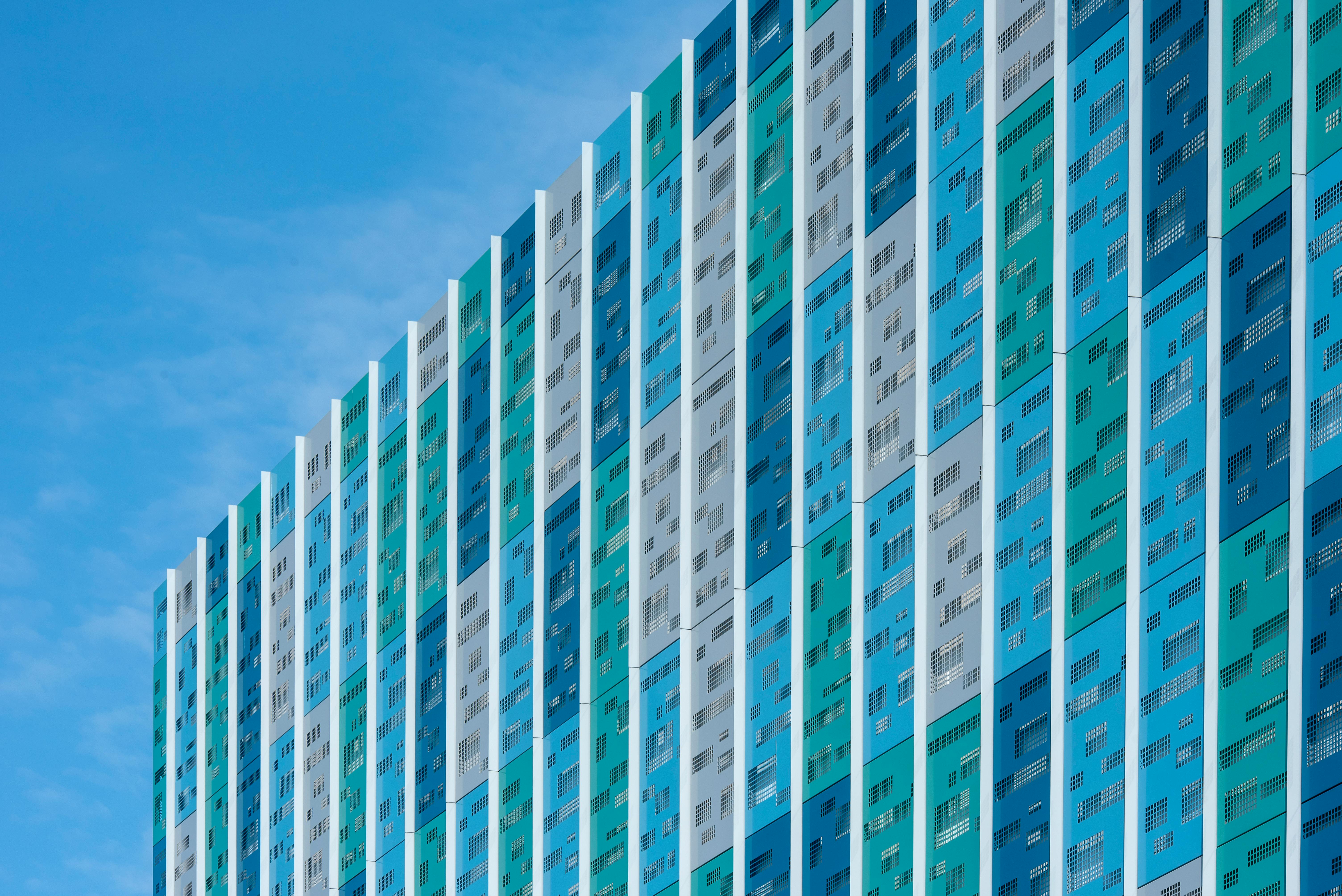 Kostenlos Lebendige geometrische Fassade eines modernen Gebäudes vor blauem Himmel, die farbenfrohe abstrakte Muster zeigt. Stock-Foto