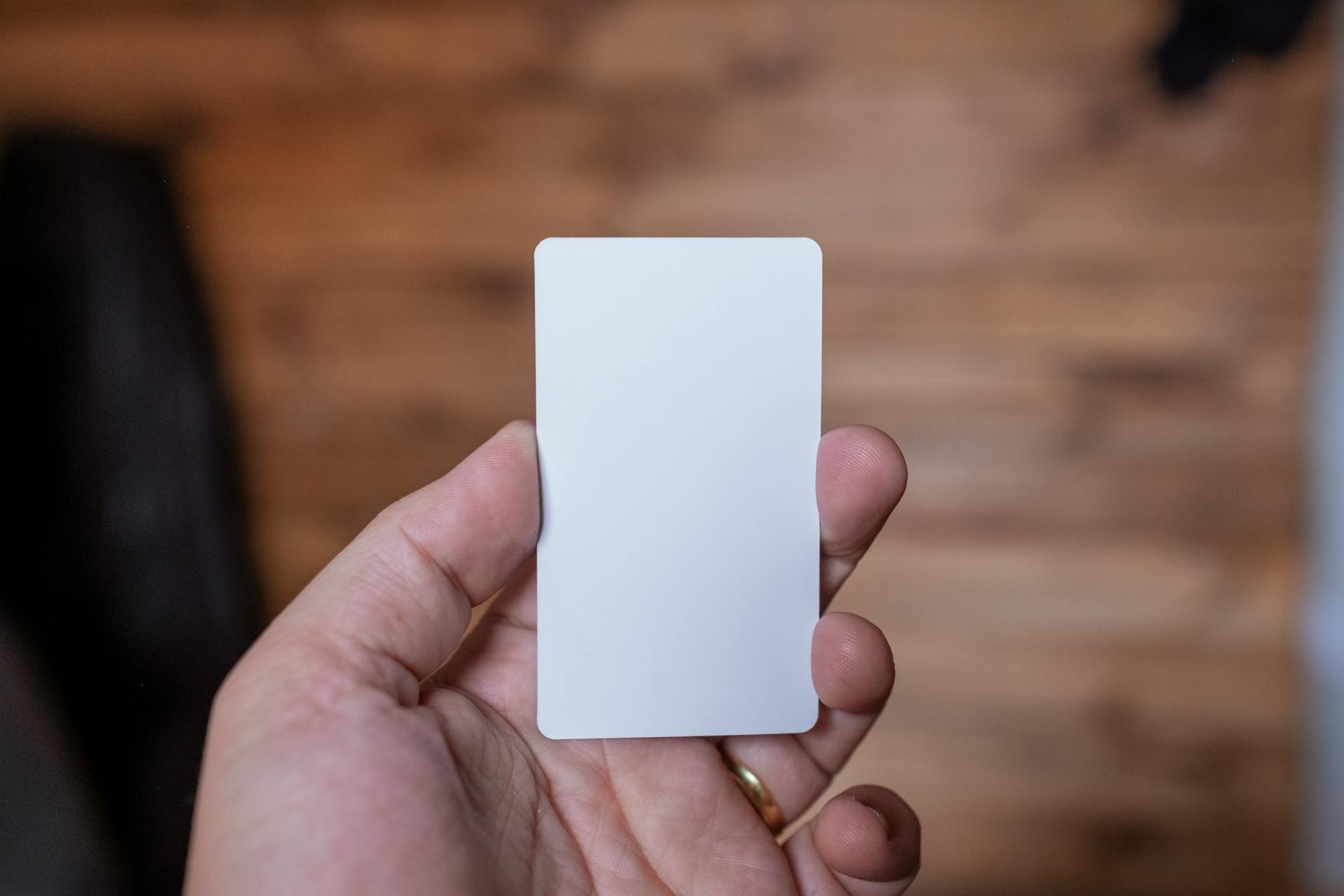 A close-up view of a hand holding a blank white card, ideal for business or creative designs.