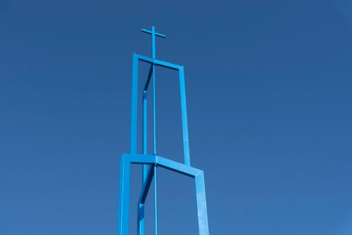 Free A minimalistic blue church tower with cross against a clear blue sky in Giessenburg, Netherlands. Stock Photo