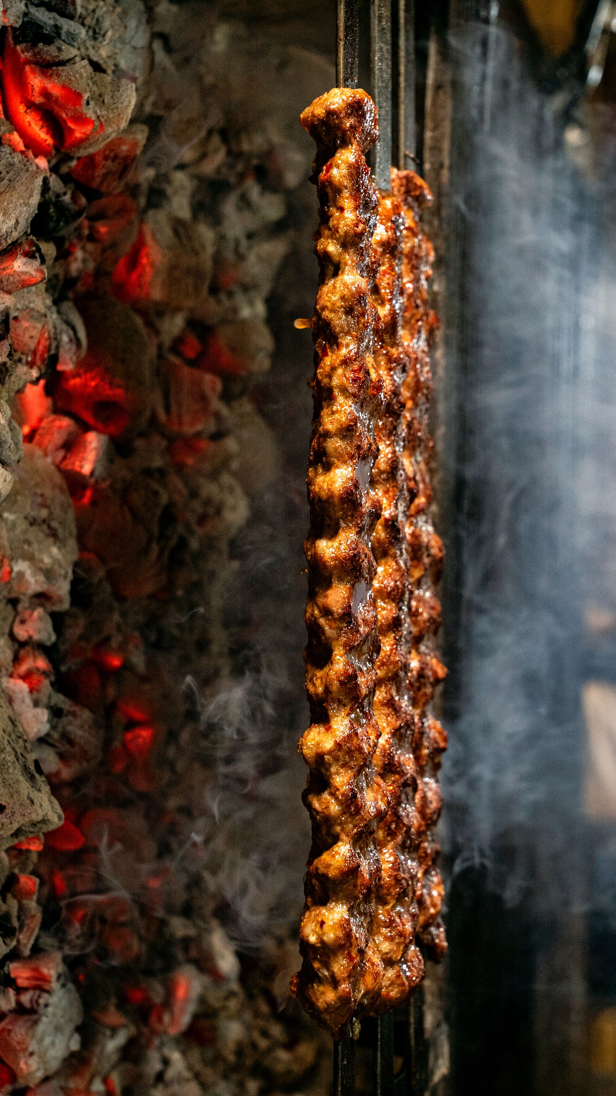 Deliciously grilled meat skewers cooking on an open flame, surrounded by smoky coals.