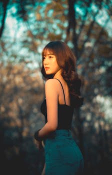 一位穿着休闲装的时尚年轻女子，在秋叶背景下于户外摆着姿势