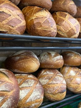 Delicious artisan bread loaves stacked on shelves in a bakery, showcasing crusty textures.