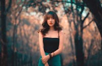 一位时尚的年轻女子在宁静的森林中优雅地摆姿势，捕捉到美丽与自然的融合