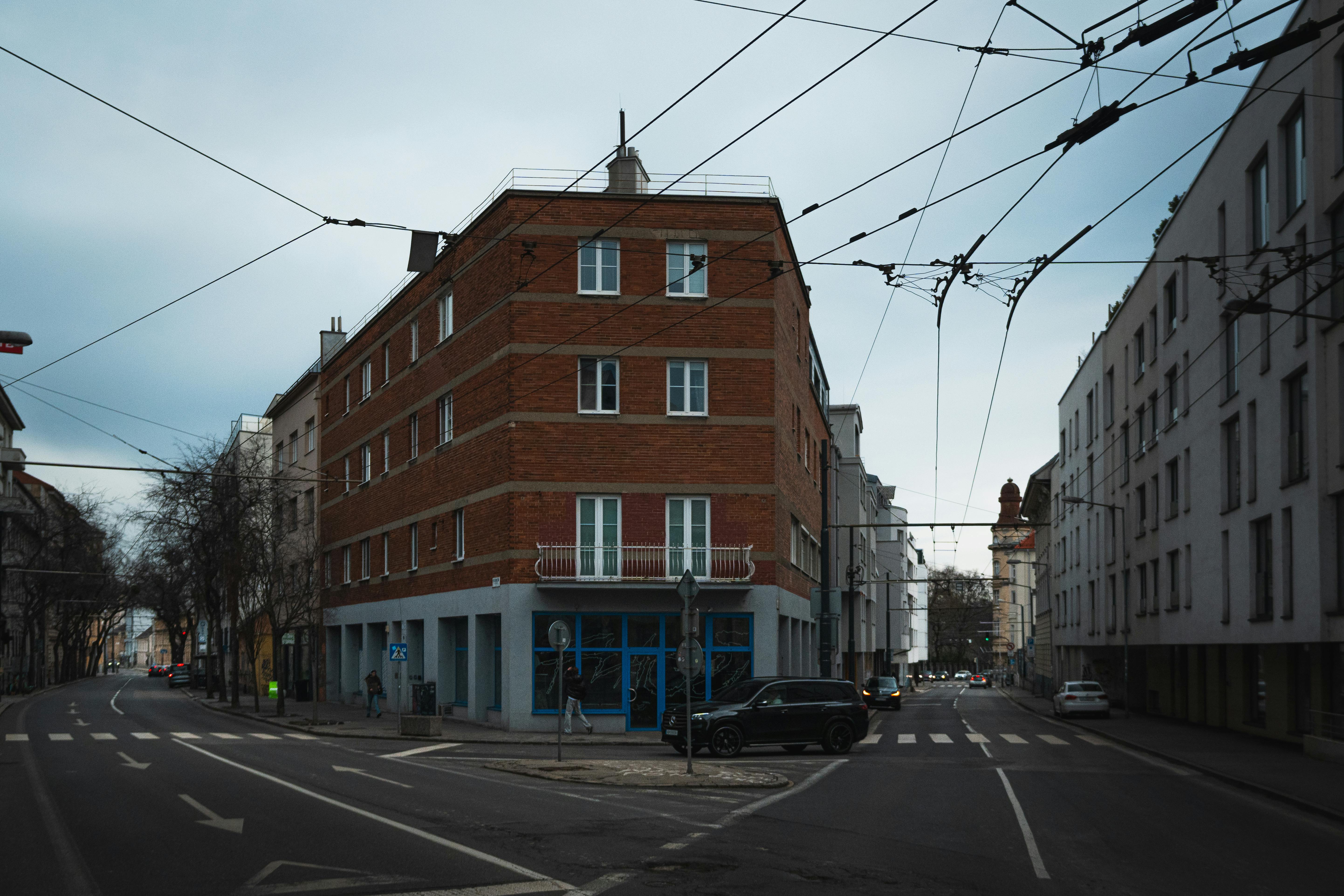 Zadarmo Červená tehlová budova na tichej križovatke mestských ulíc s nadzemnými káblami. Fotka z fotobanky