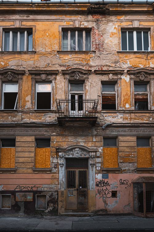 Free Weathered facade of an abandoned building with graffiti and boarded windows. Stock Photo