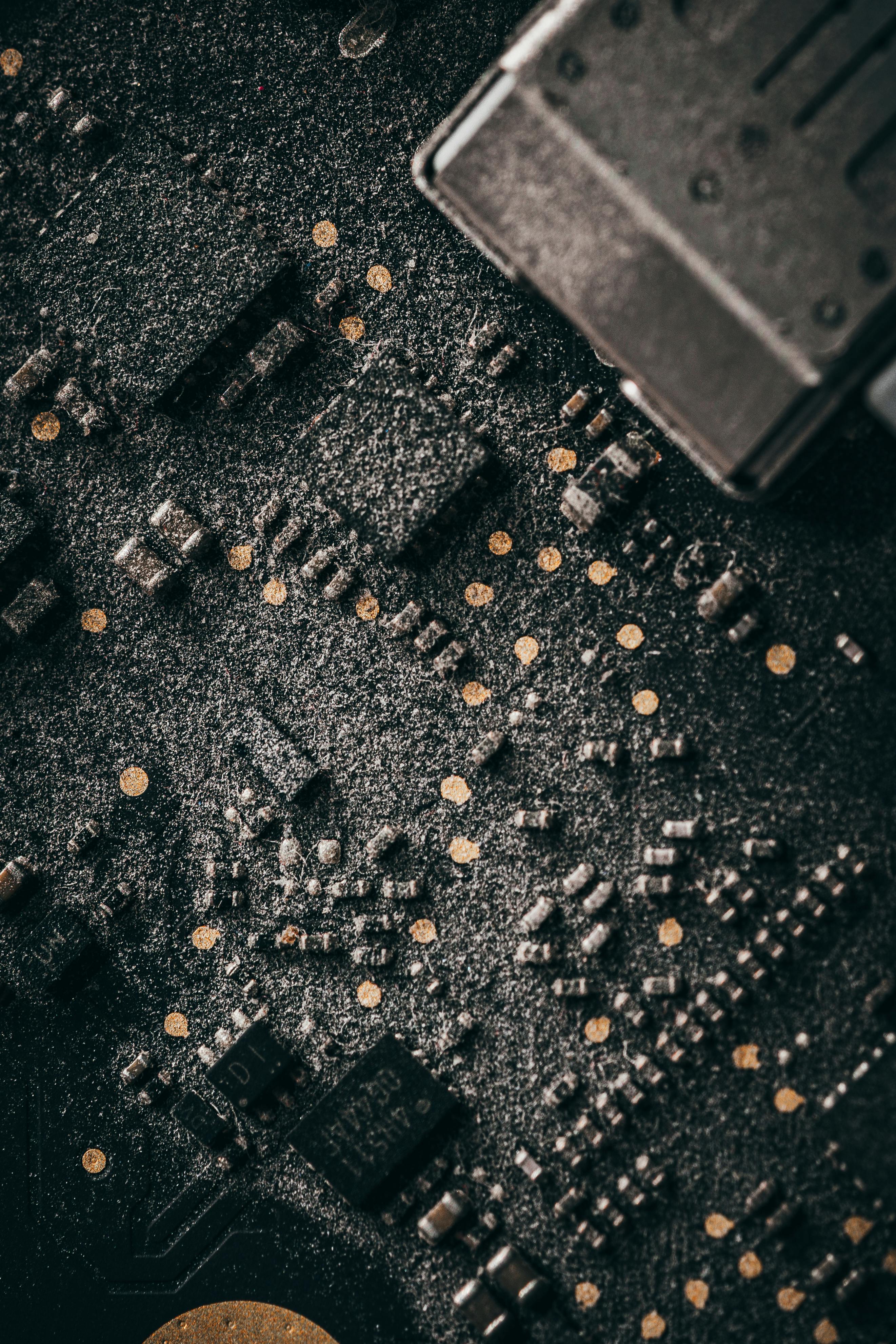Macro shot of a dusty computer circuit board with intricate components and connectors.