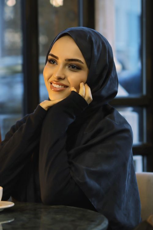 Free A young woman in a hijab smiles warmly at a cafe interior. Stock Photo