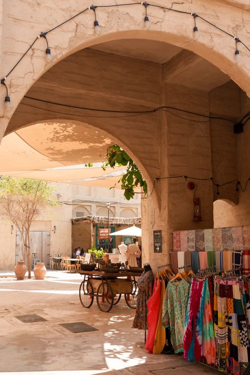 Free Vibrant textiles displayed in a market stall under ancient arches in Dubai's traditional souk. Stock Photo