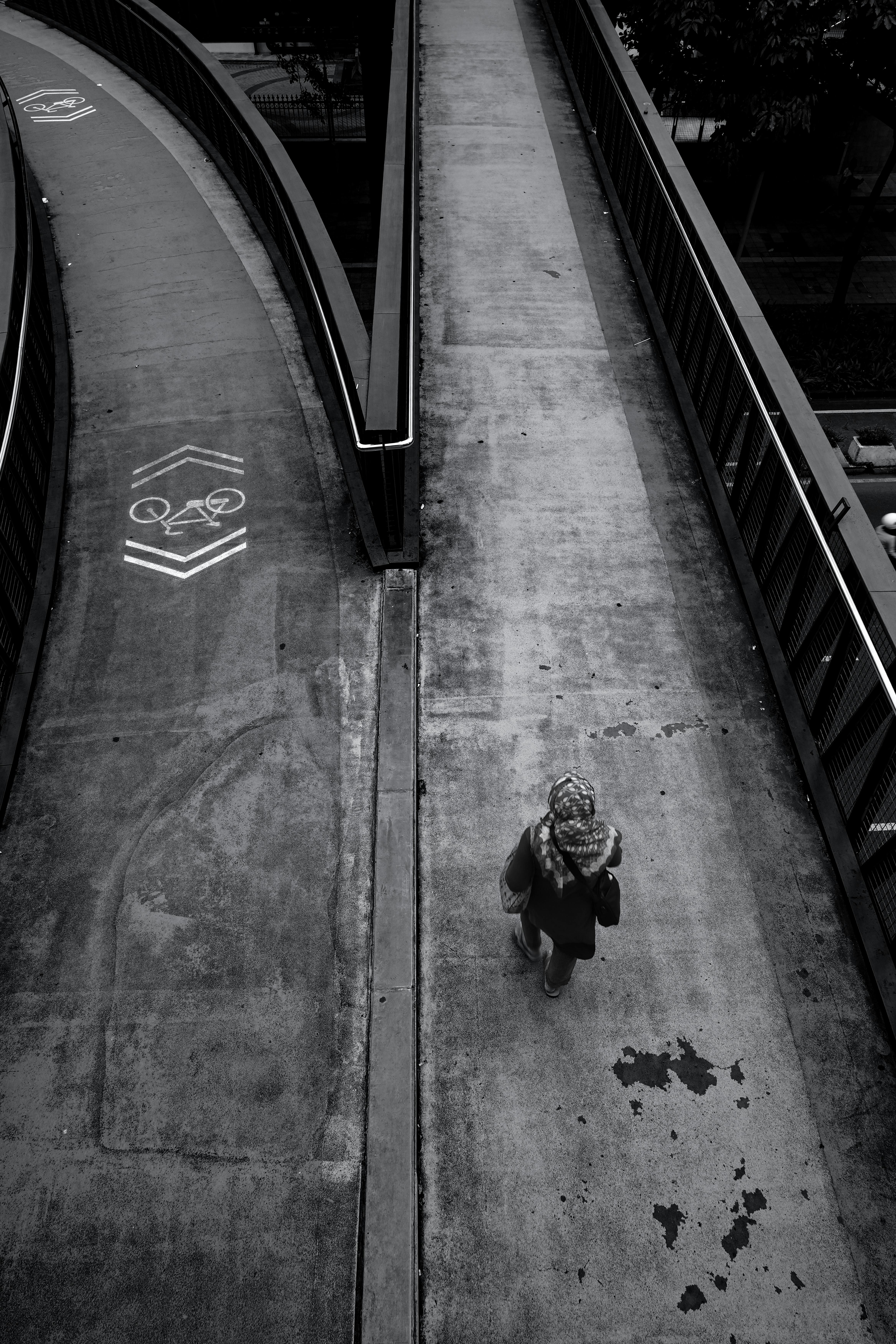 Bezpłatne Czarno-białe ujęcie osoby idącej kładką dla pieszych w Dżakarcie, w Indonezji. Zdjęcie z galerii