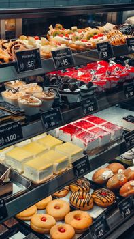 Delicious assortment of pastries and cakes displayed in a bakery with price tags.