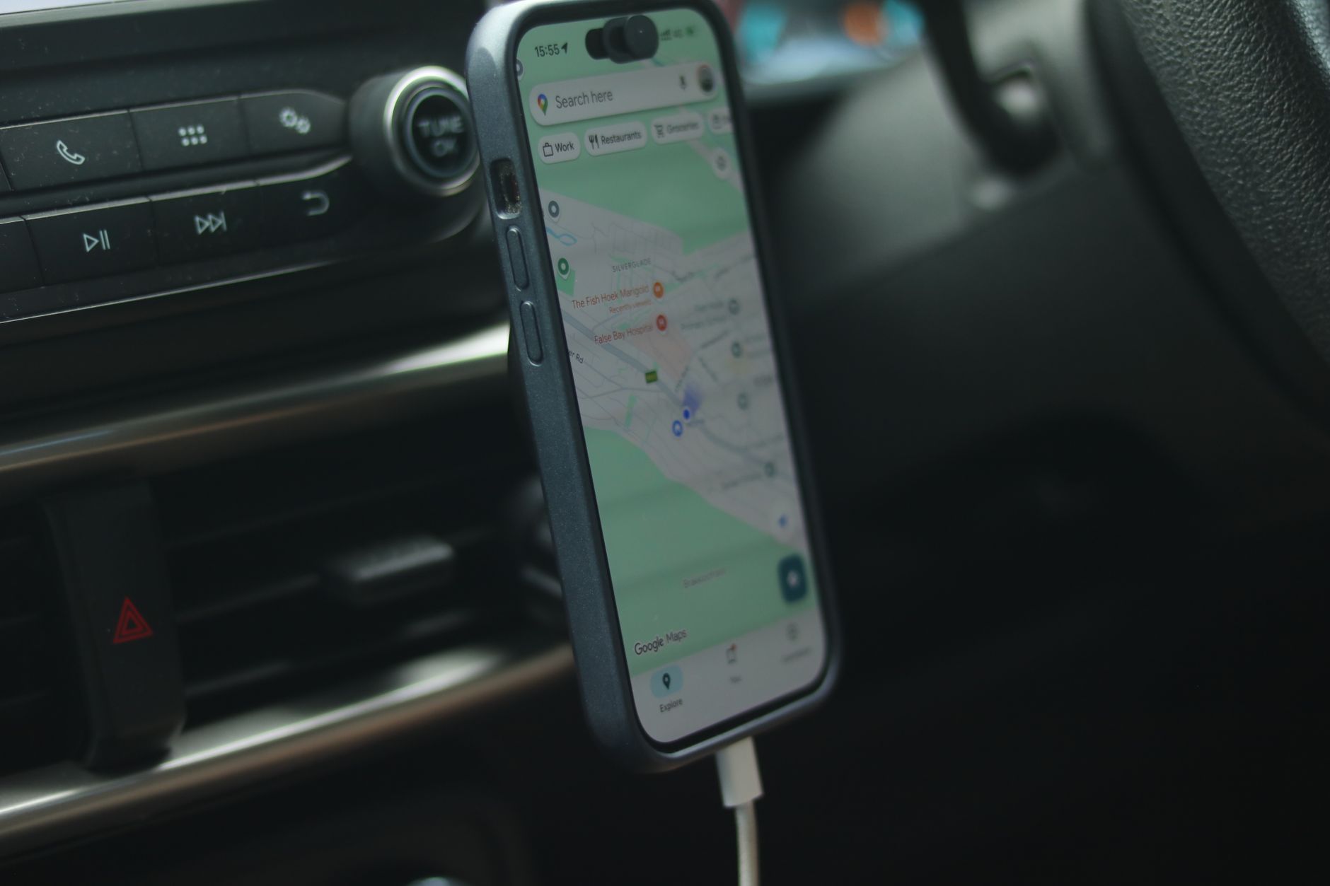 A smartphone with a map app displayed inside a car, showing modern navigation.