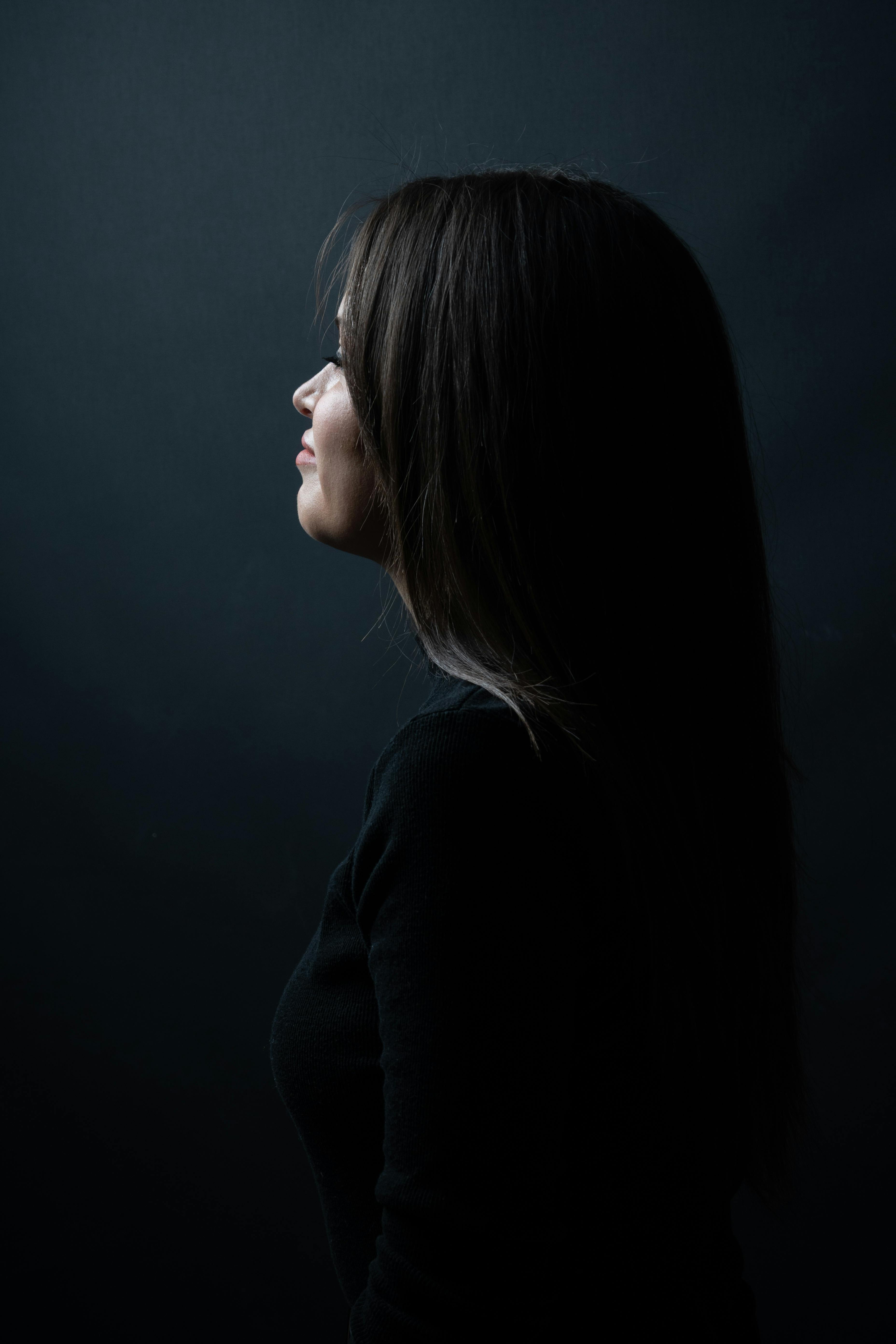 Free Artistic side profile of a woman in shadowy light, creating a moody ambiance. Stock Photo