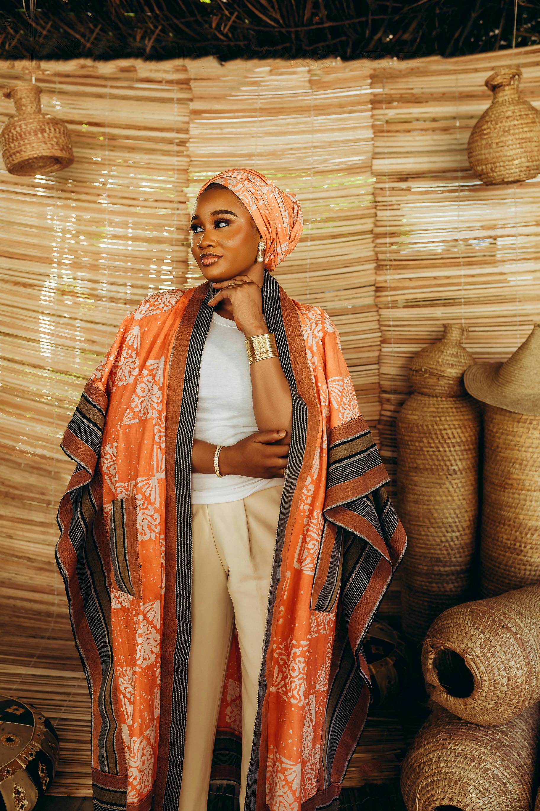 ฟรี หญิงสาวในชุดแอฟริกันสีสันสดใสกำลังโพสท่าถ่ายรูปกับตะกร้าสานภายในบ้าน คลังภาพถ่าย