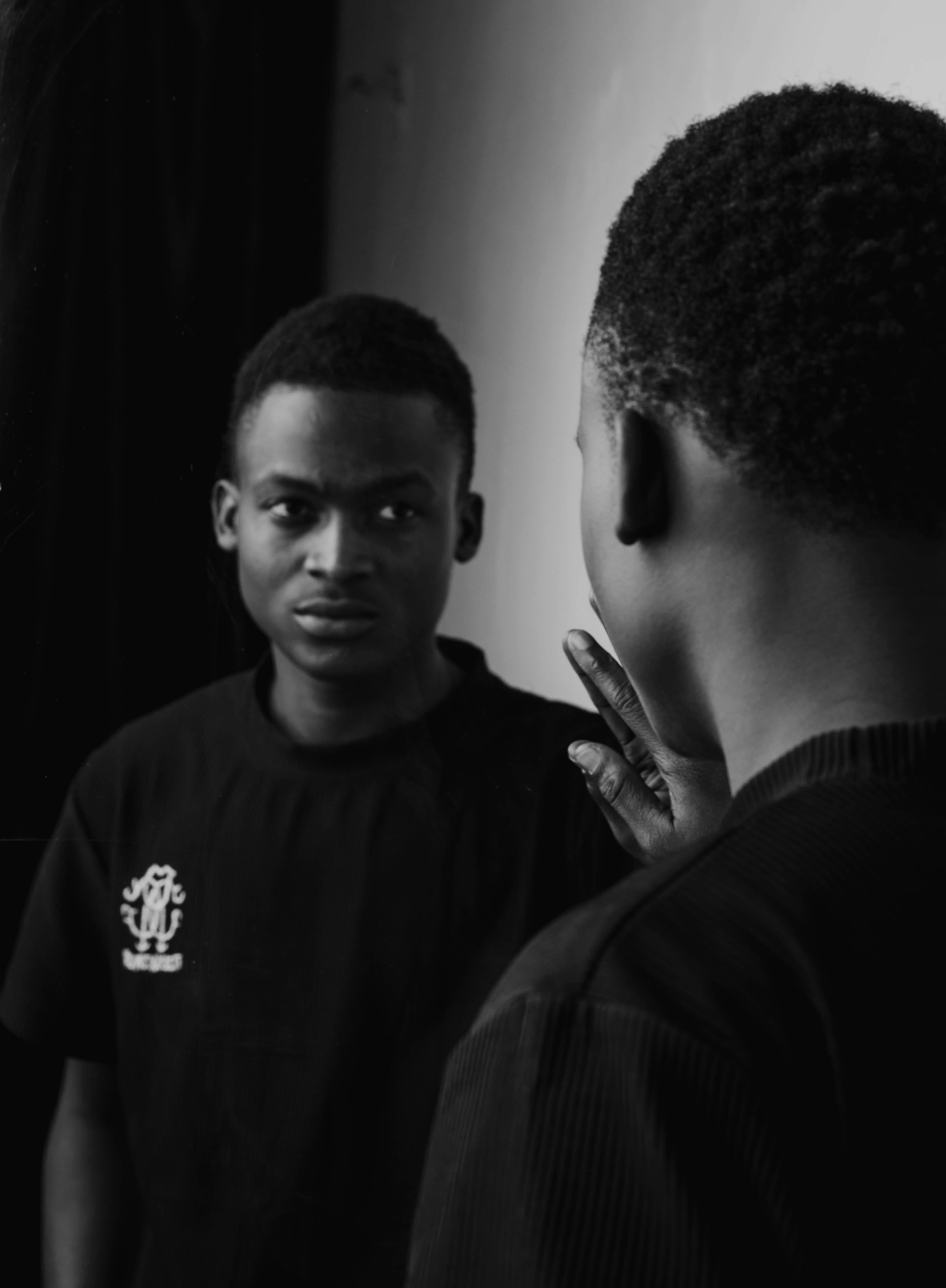 Free Black and white portrait of a man looking at his reflection in a mirror. Stock Photo