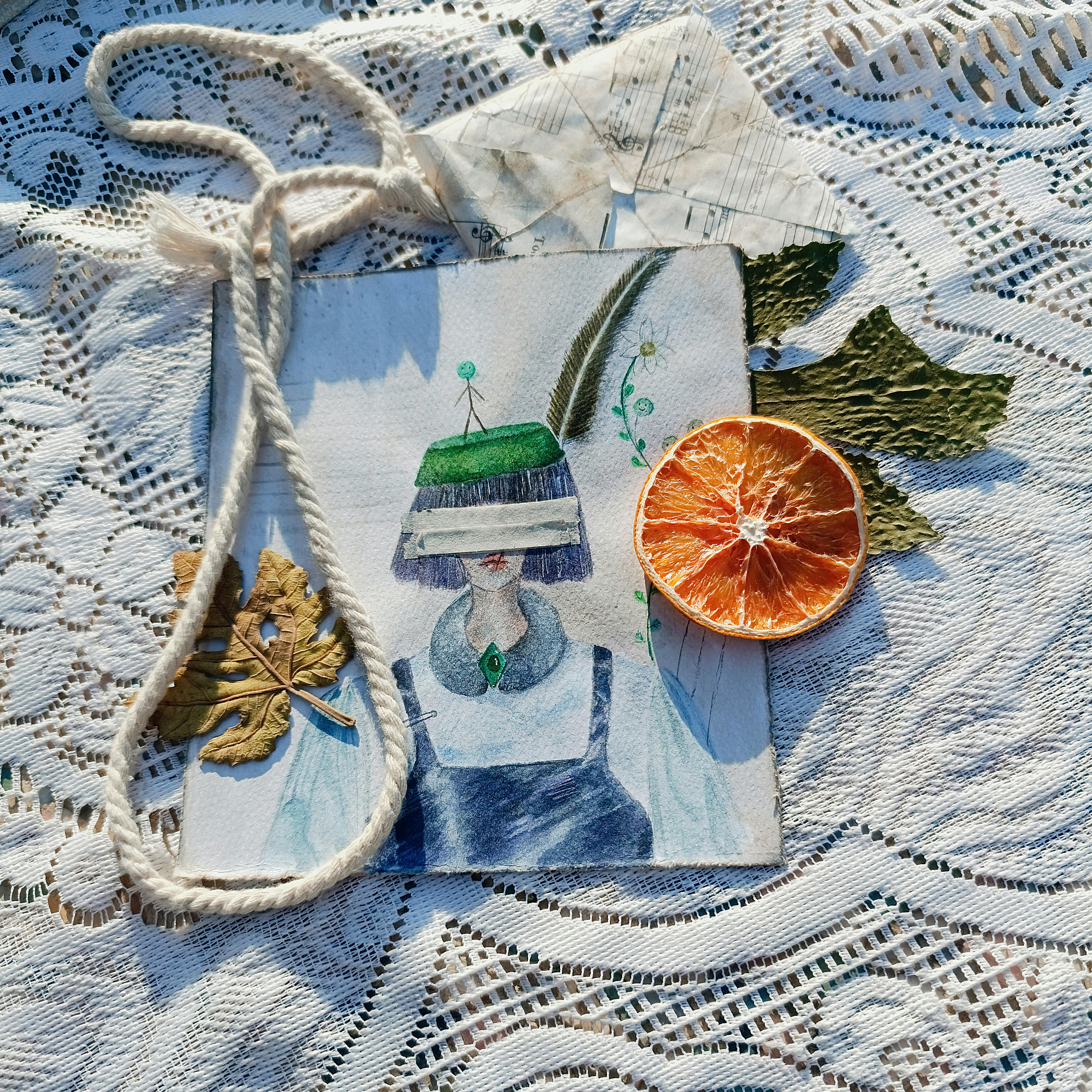 A creative still life with a surreal illustration, dried orange, and lace texture.