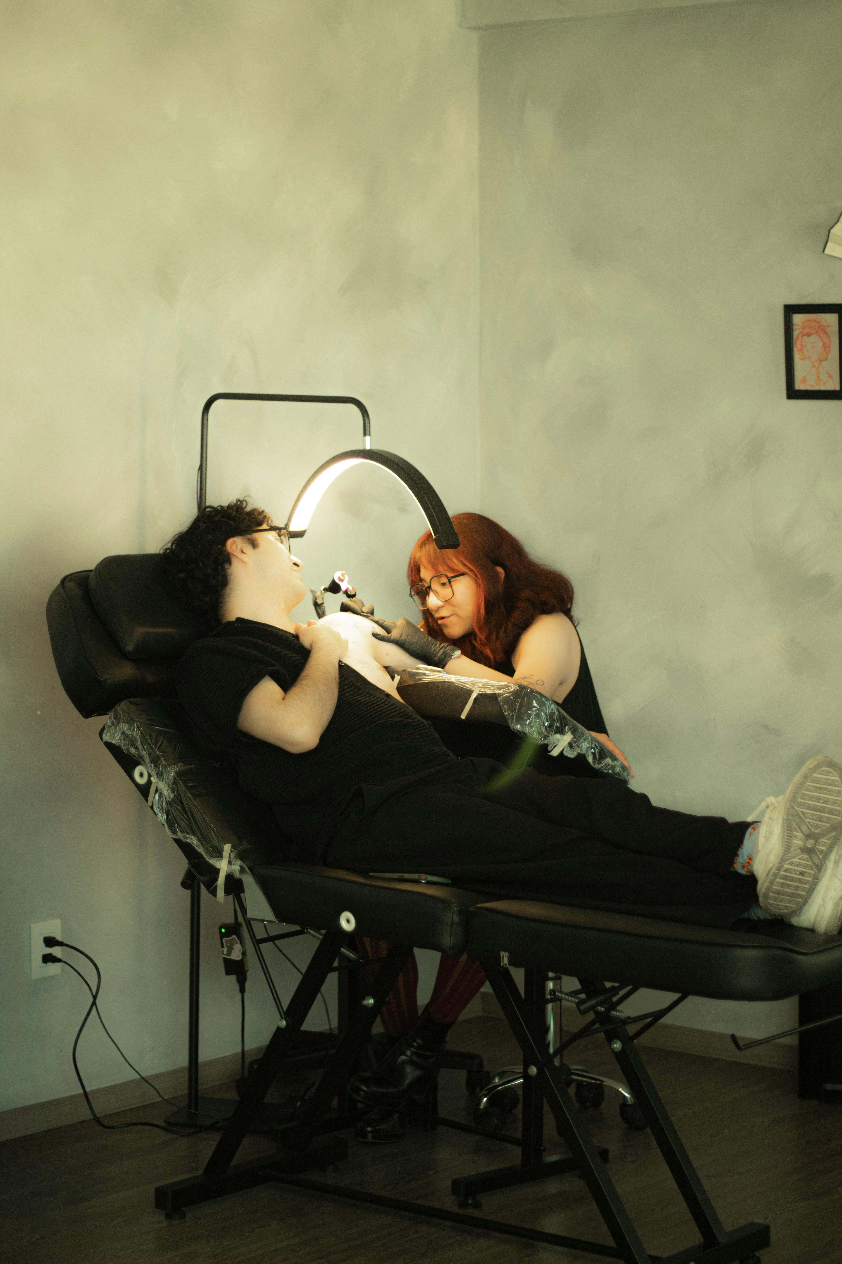 ฟรี ช่างสักมืออาชีพที่มุ่งเน้นการสร้างสรรค์งานศิลปะบนแขนของลูกค้าในสตูดิโอที่ทันสมัย คลังภาพถ่าย