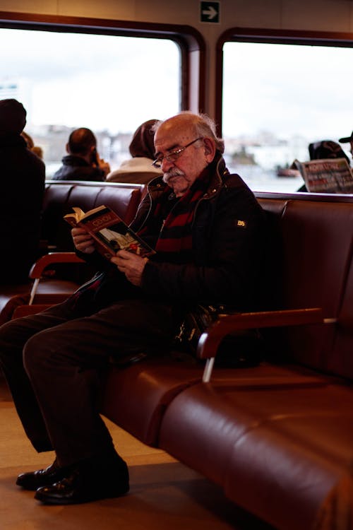 무료 빨간 가죽 의자에 앉아 검은 재킷을 입은 남자 스톡 사진