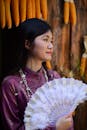 Woman in Traditional Attire Holding a Lace Fan