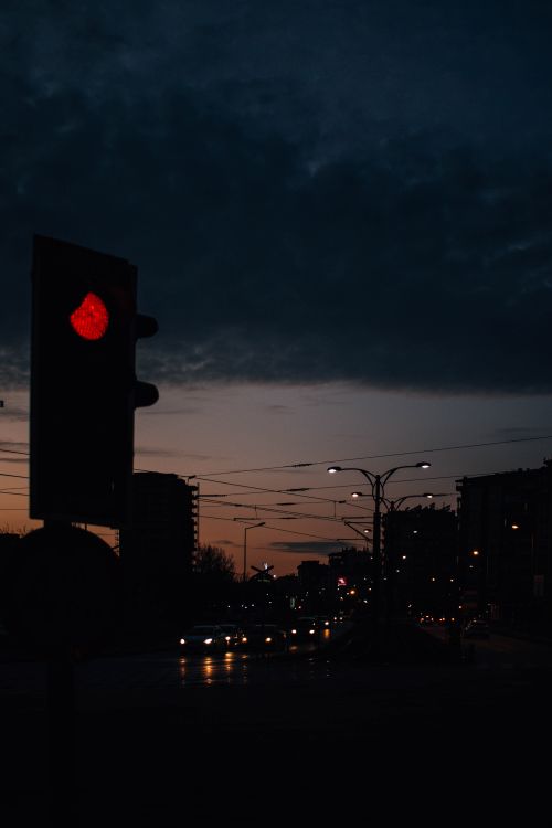 Free Urban traffic scene with a red stoplight silhouetted against a dramatic dusk sky. Stock Photo