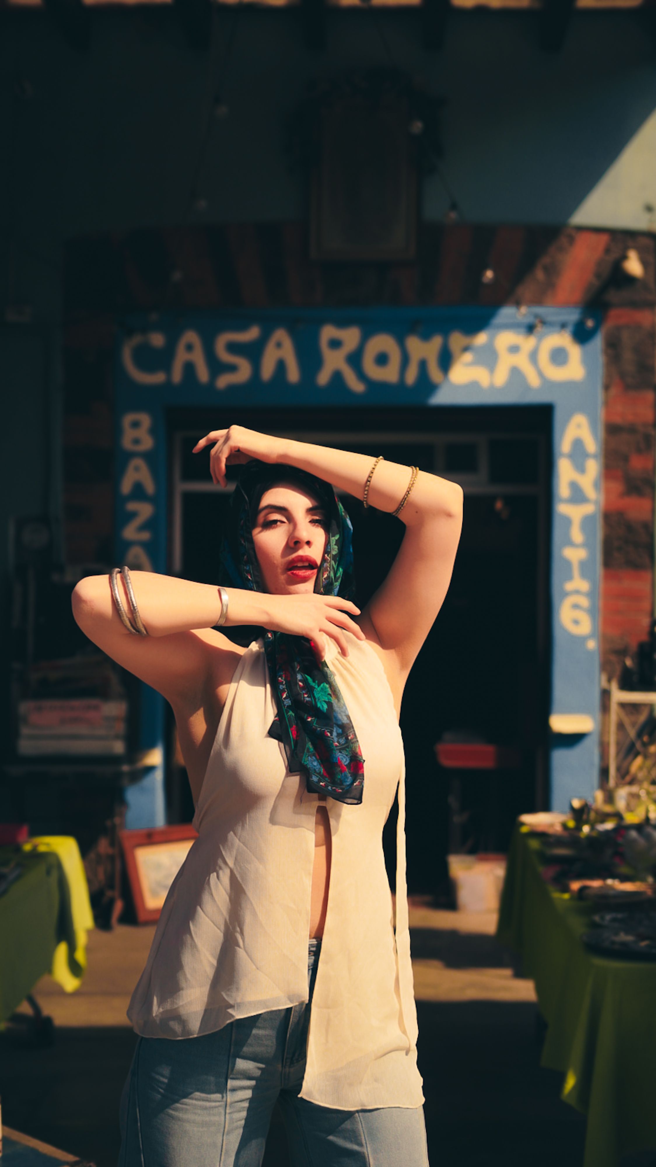 A woman posing stylishly outside Casa Romero antiques store in a vibrant bazaar setting.