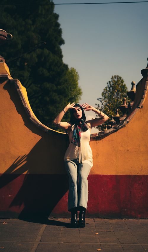 Free Woman in stylish outfit posing against a colorful wall outdoors in sunny weather. Stock Photo