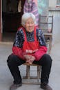 Elderly Woman Sitting on a Stool Outdoors